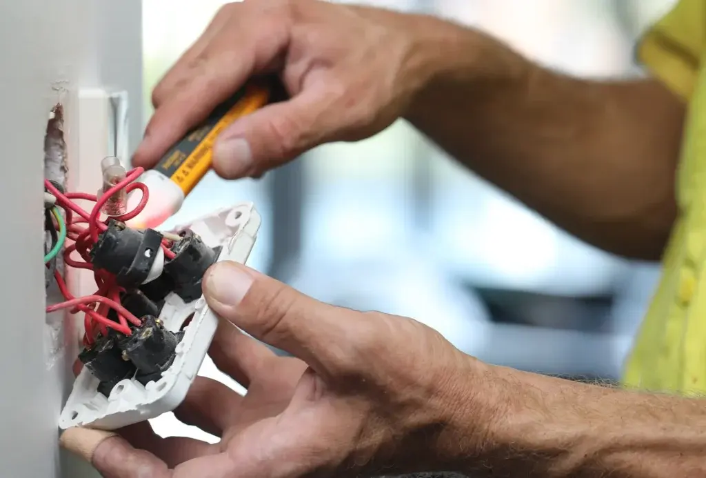 Electrician checking wiring at a wall switch